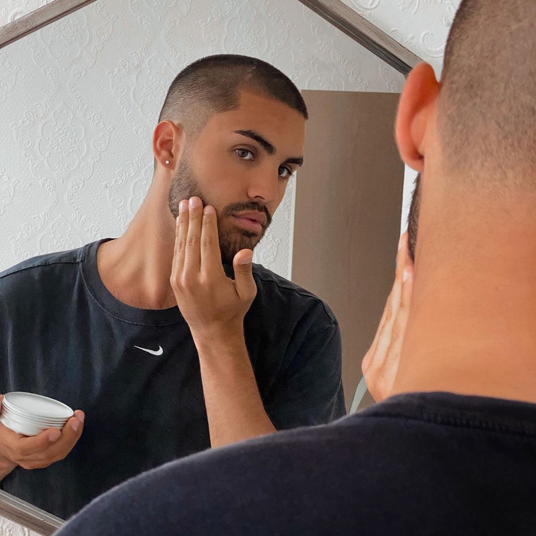 Man styling his bear in the mirror